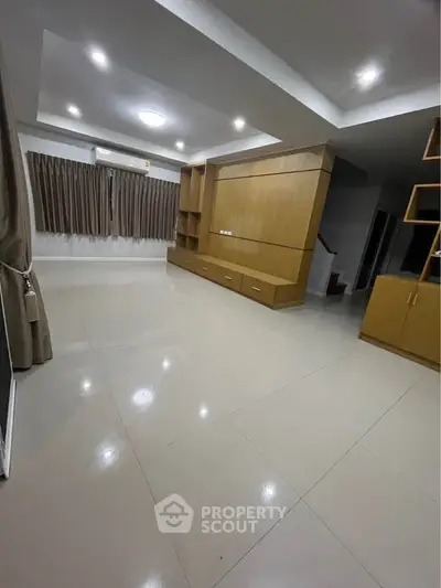Spacious modern living room with sleek tile flooring and built-in wooden cabinetry.