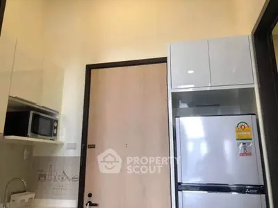 Modern kitchen with sleek cabinetry, microwave, and refrigerator in a compact layout.