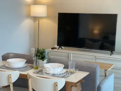 Modern living room with stylish dining area and large flat-screen TV.