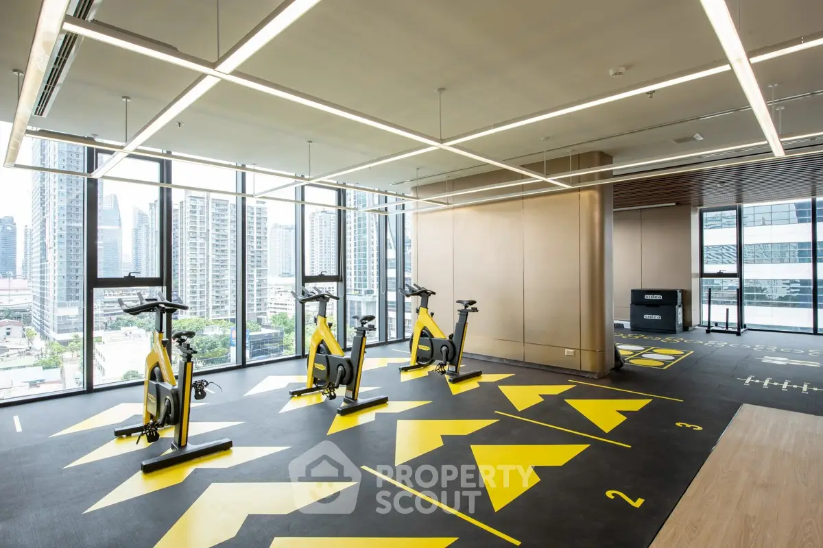 Modern gym with city view, featuring exercise bikes and sleek design.