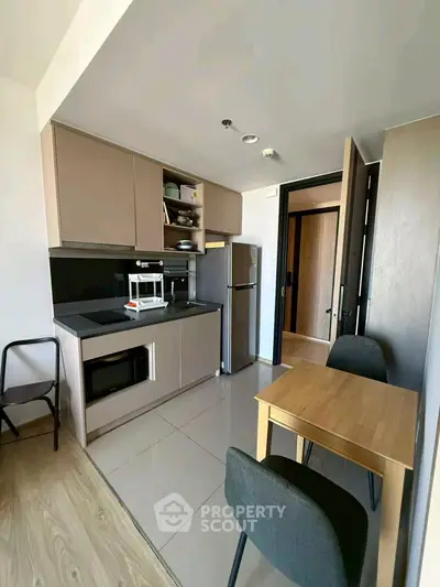 Modern kitchen with sleek cabinetry, compact dining area, and integrated appliances in a stylish apartment.