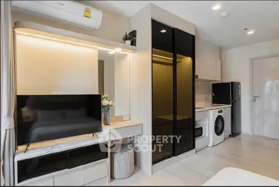 Modern studio apartment with sleek design, featuring a compact kitchen, washing machine, and stylish TV setup.