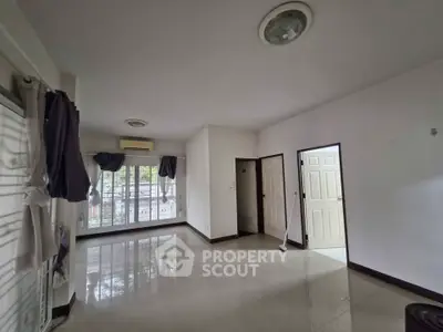 Spacious empty living room with large windows and balcony access, perfect for customization.