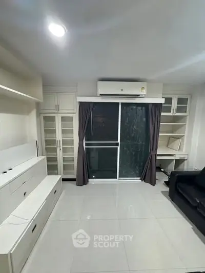 Modern living room with sleek white cabinetry and large window for natural light.