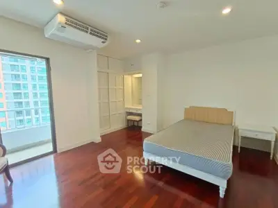 Spacious bedroom with hardwood floors and balcony access in modern apartment.