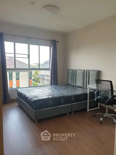 Bright bedroom with large window and modern furnishings in a stylish apartment.