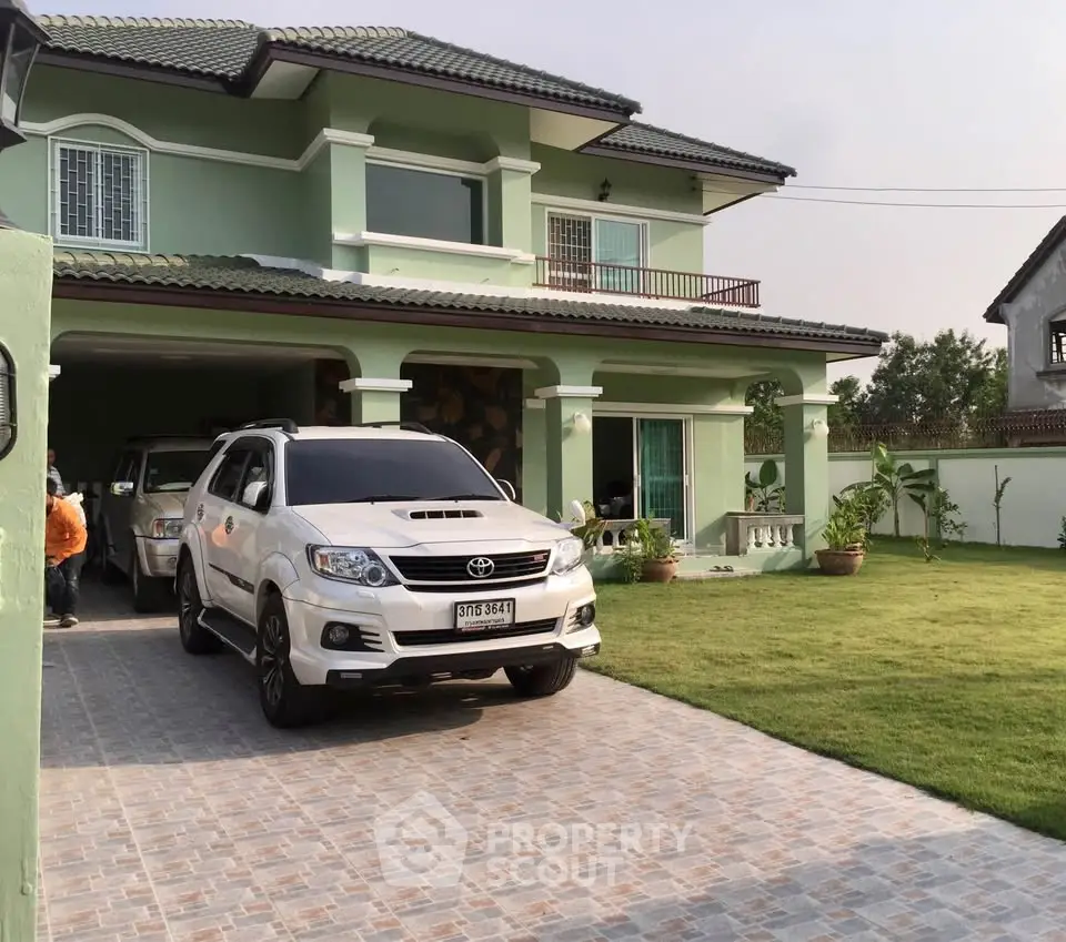 Spacious two-story green house with driveway and lush lawn, perfect for family living.