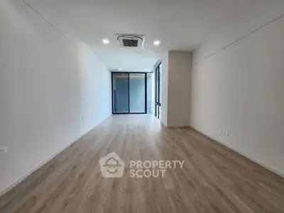 Spacious modern living room with wooden flooring and large windows for natural light.