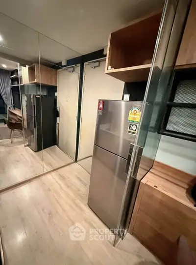 Modern apartment interior with mirrored walls and sleek kitchen appliances.