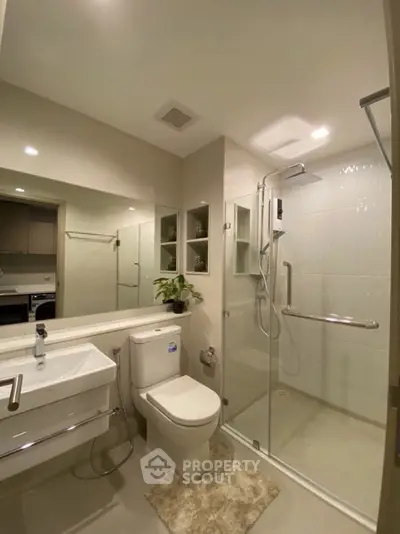 Modern bathroom with glass shower, sleek fixtures, and elegant lighting.