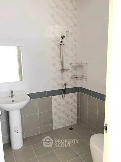 Modern bathroom with sleek shower and pedestal sink in neutral tones.