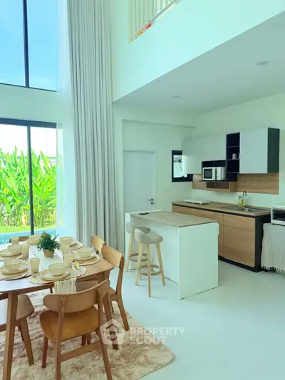 Modern open-layout kitchen and dining area with high ceilings and large windows