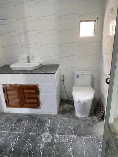 Modern bathroom with sleek tile flooring and compact sink-toilet setup.