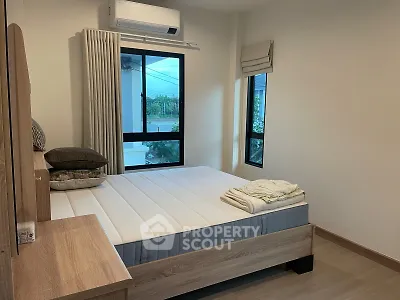 Cozy bedroom with modern furnishings and large windows offering natural light.
