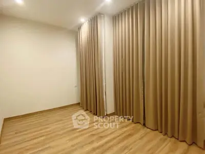 Spacious empty room with elegant wooden flooring and floor-to-ceiling curtains, perfect for customization.