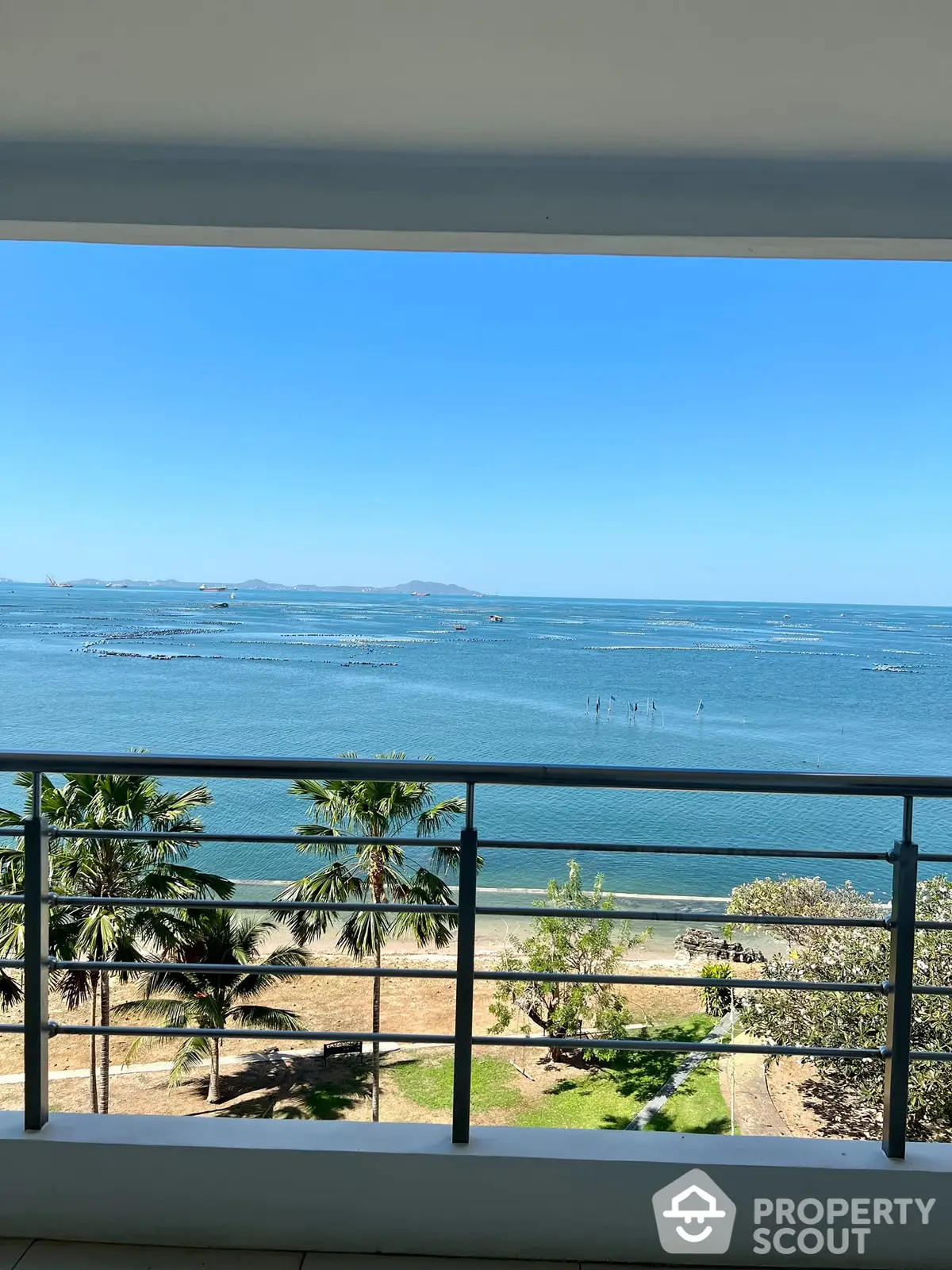 Breathtaking oceanfront view from a spacious balcony, offering serene sea vistas and lush greenery, ideal for tranquil living and entertaining guests.