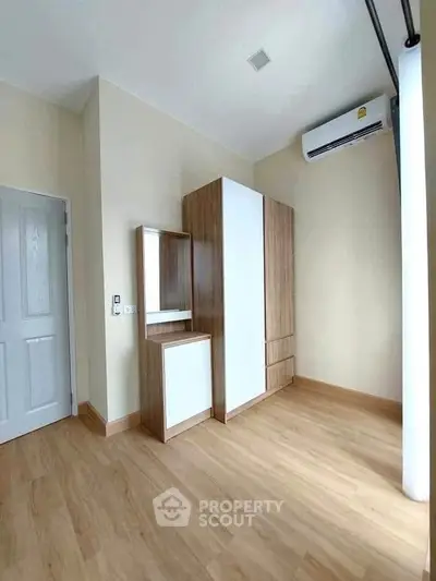Spacious bedroom with wooden wardrobe and air conditioning in modern apartment.