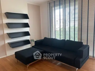 Modern living room with sleek black sofa and wall-mounted shelves