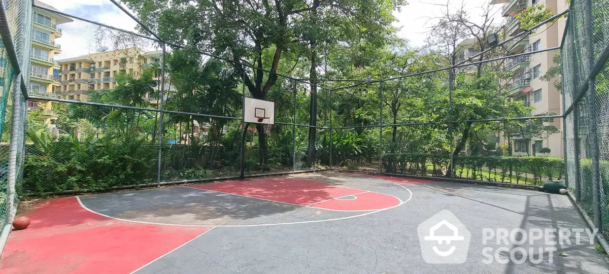 Spacious outdoor basketball court nestled among lush greenery within a residential complex, offering a perfect blend of fitness and leisure.