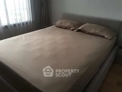 Cozy bedroom with a neatly made bed and soft natural light from the window.