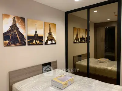 Cozy bedroom with mirrored closet and Eiffel Tower artwork, perfect for relaxation.