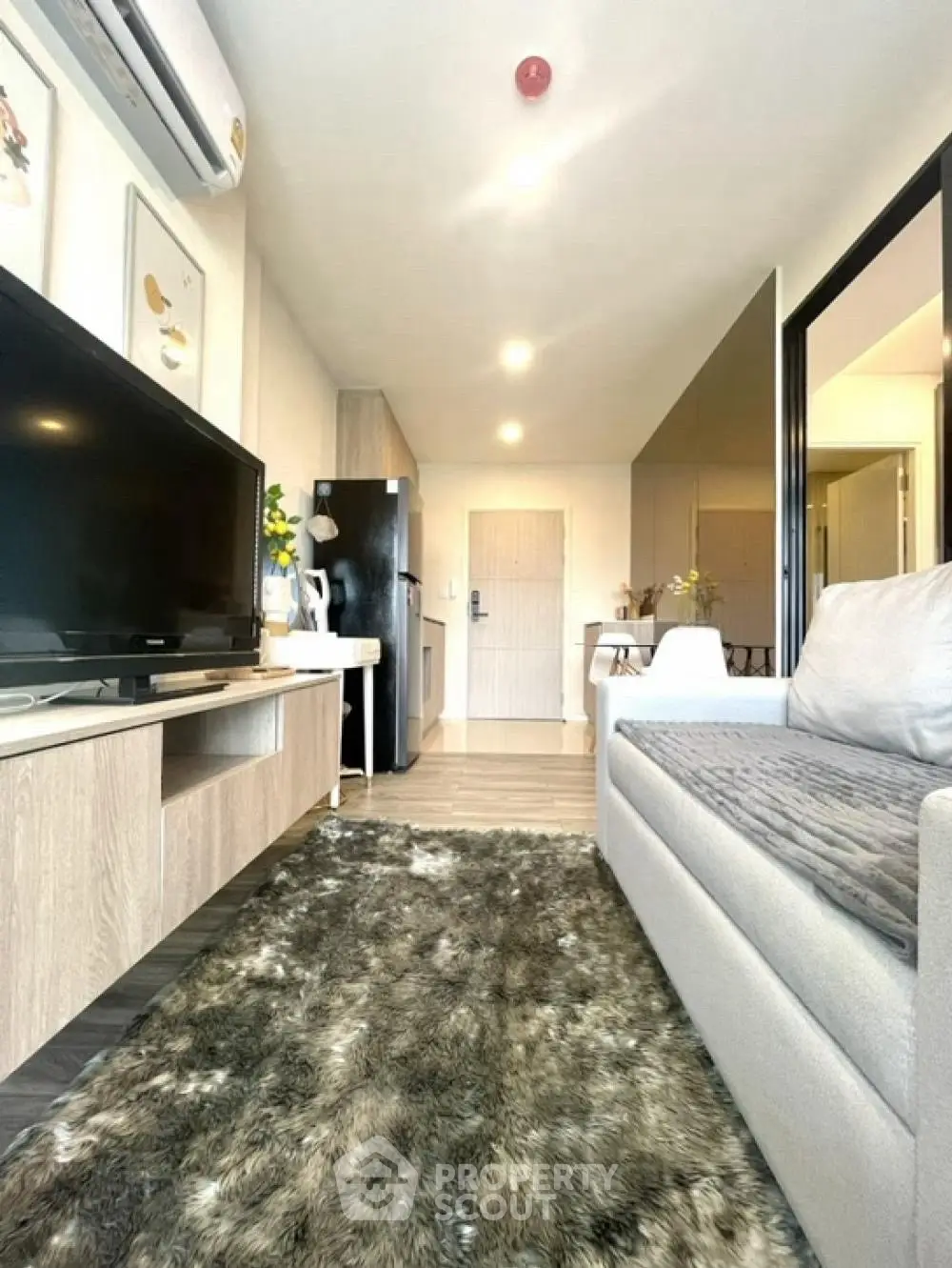 Modern living room with cozy sofa, stylish TV unit, and plush rug in a contemporary apartment.