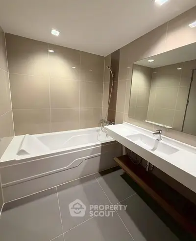 Modern bathroom with sleek bathtub and large mirror in elegant design.