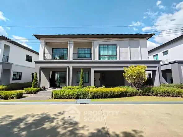 Modern two-story house with landscaped garden and clear blue sky