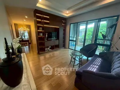 Spacious living room with elegant decor and large windows opening to a lush balcony view.