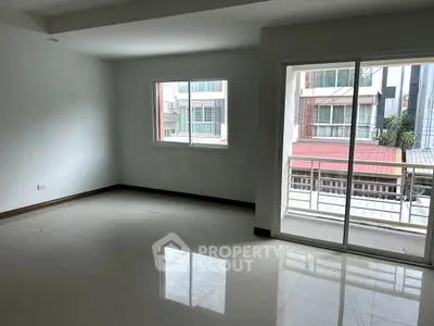 Spacious unfurnished living room with large windows and balcony access in modern apartment.
