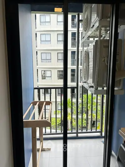 Modern balcony with air conditioning units and drying rack overlooking apartment complex.