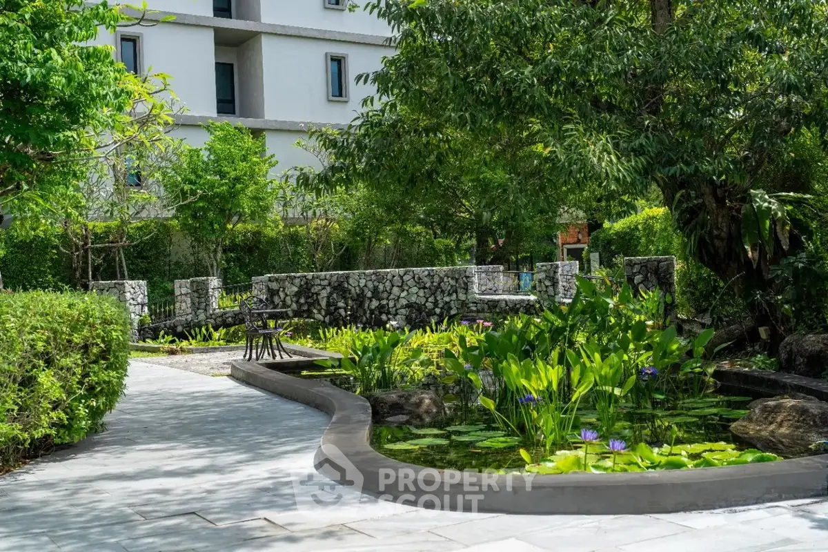 Serene garden view with lush greenery and stone pathways in a modern residential complex.