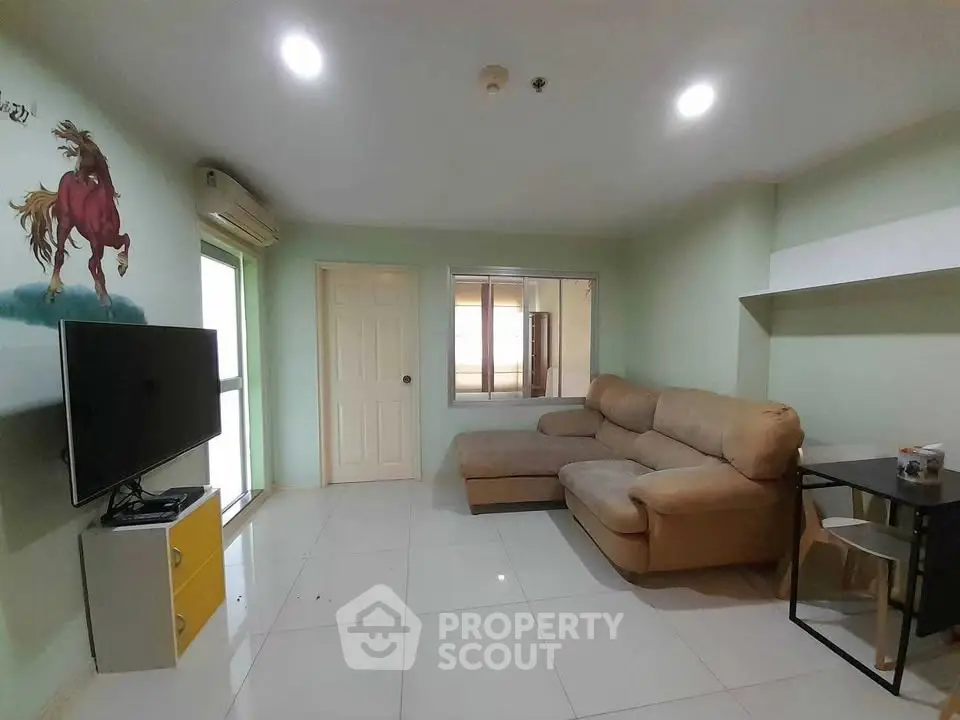 Spacious living room with modern sofa and wall-mounted TV in a cozy apartment.