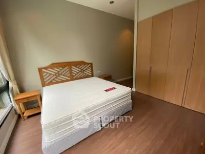 Spacious bedroom with wooden flooring and large window in modern apartment.