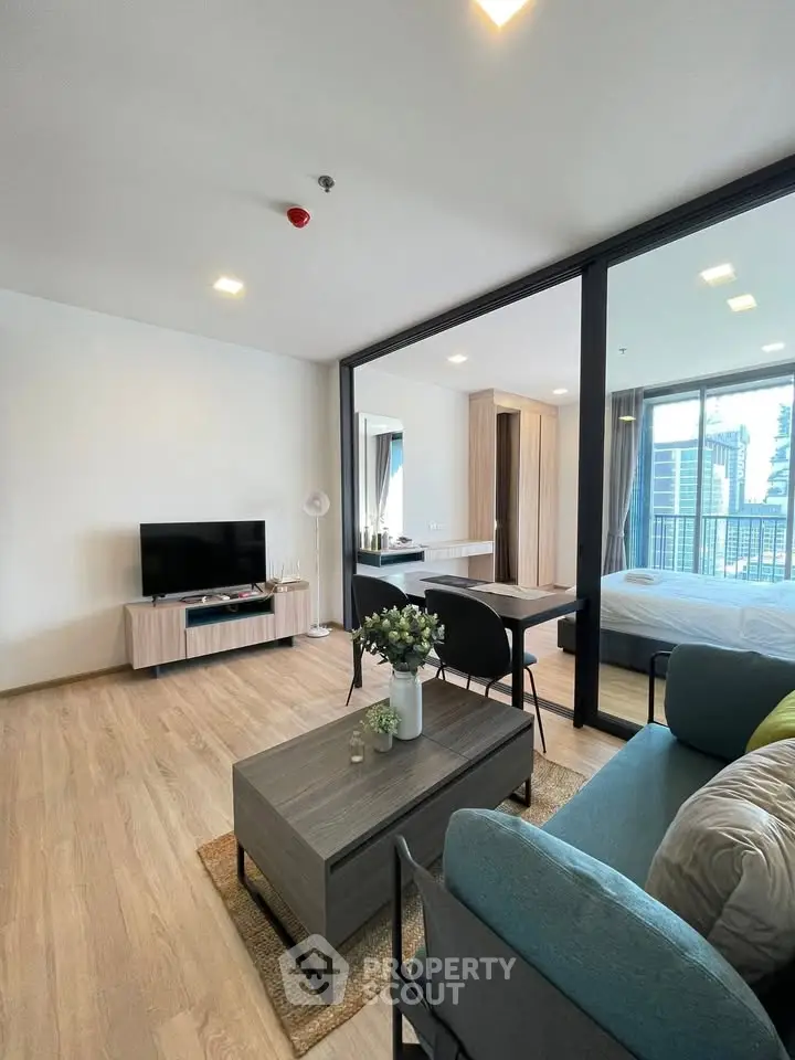 Modern living room with open layout and city view, featuring stylish furniture and natural light.