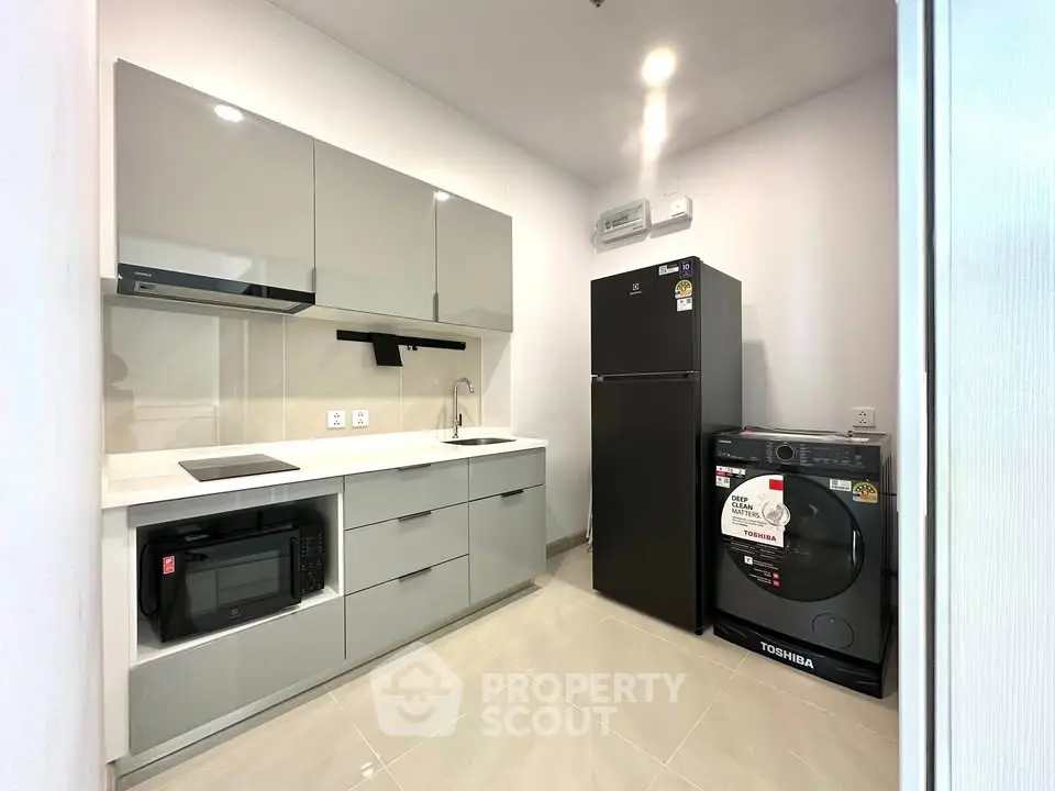 Modern kitchen with sleek cabinetry, appliances, and tiled flooring in a contemporary apartment.