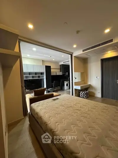 Modern studio apartment with open layout, featuring a cozy bed, stylish kitchen, and washing machine.
