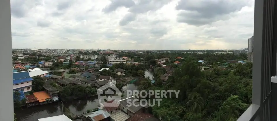 Panoramic view of lush greenery and urban landscape from a high-rise building.