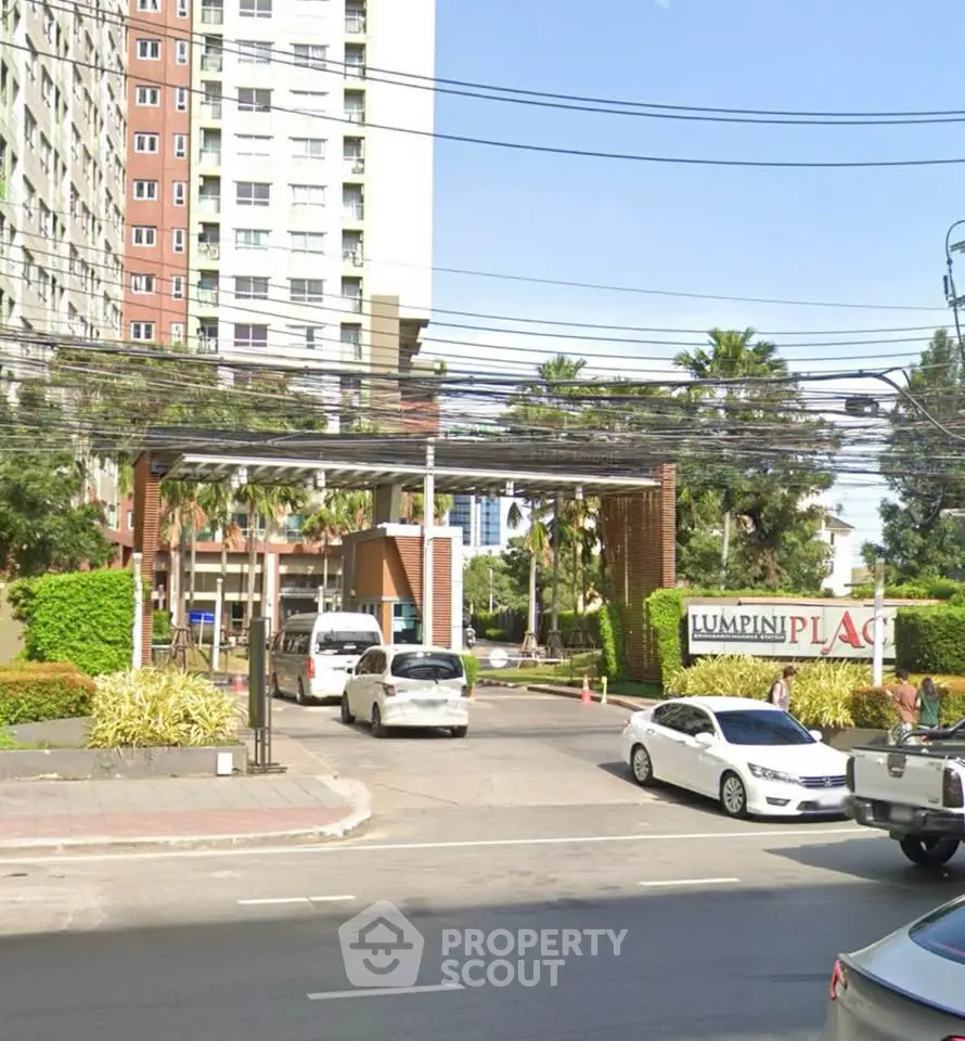 Modern condominium entrance with lush greenery and secure gated access.