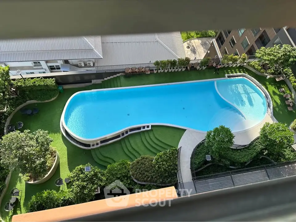 Stunning aerial view of a luxurious residential swimming pool surrounded by lush greenery and modern architecture.