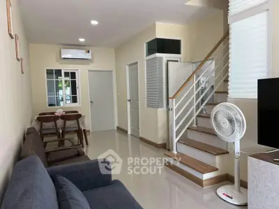 Modern living room with staircase, dining area, and air conditioning in a cozy home.