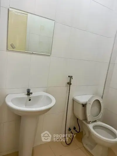 Modern bathroom with white tiles and essential fixtures, ideal for compact spaces.