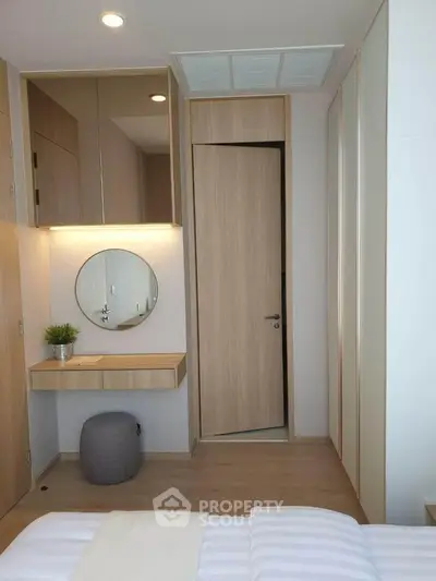Modern bedroom with minimalist design, featuring a stylish vanity and mirror, light wood accents, and cozy ambiance.