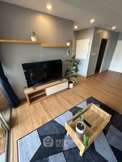Modern living room with wooden flooring, stylish TV unit, and indoor plants for a cozy ambiance.
