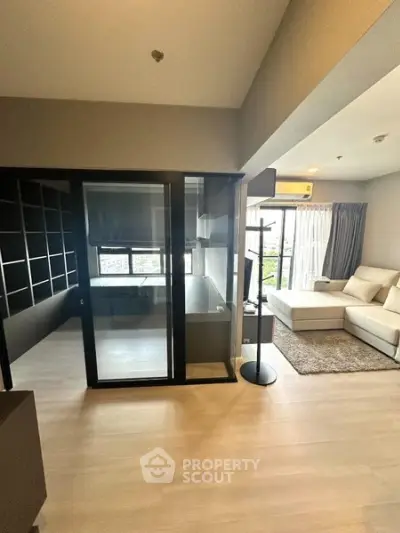 Modern living room with glass partition and cozy seating area in a high-rise apartment.