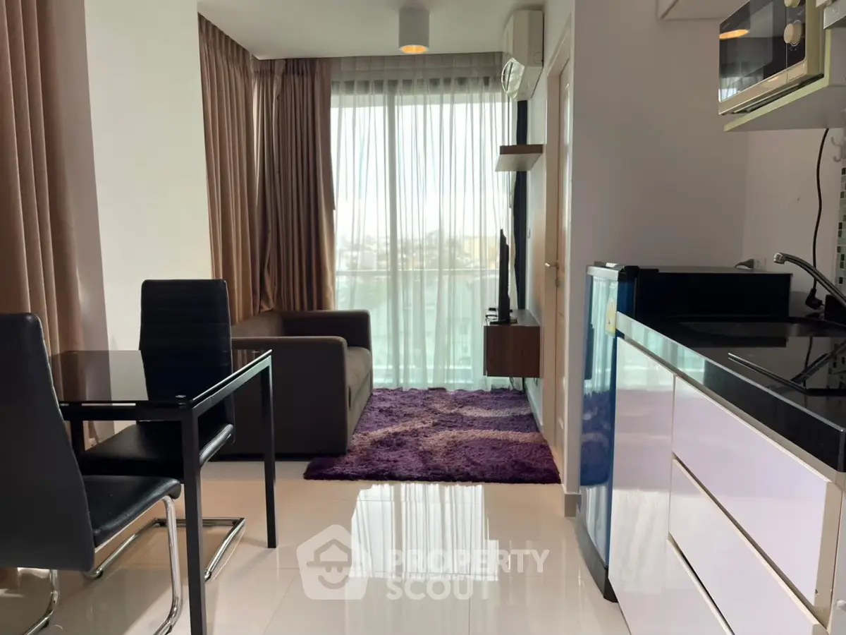 Modern open-plan living room with sleek kitchen and balcony view in stylish apartment.
