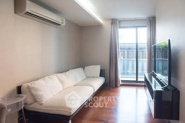 Cozy modern living room with large window and sleek furniture, perfect for relaxation.
