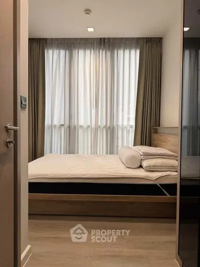 Cozy bedroom with large window and modern furnishings, perfect for relaxation.