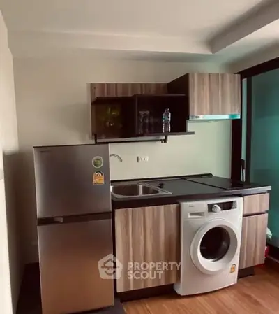 Compact modern kitchen with fridge and washing machine in stylish apartment.