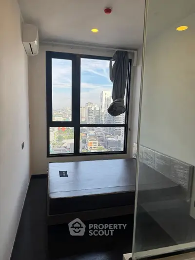 Modern bedroom with large window offering stunning city view, featuring minimalist design and air conditioning.